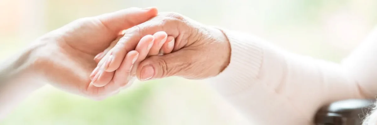 Pflege-Info-Header Pflegekraft hält eine Hand eines älteren Menschen